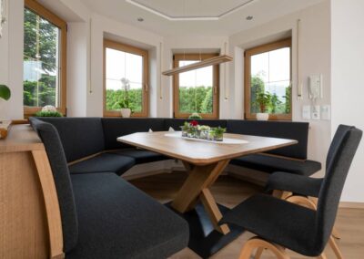 Hier verbindet sich Tradition mit Moderne. Eine modern gestaltete Eckbank – schwarz gepolstert – in einem traditionellen Erker eingebaut und ein perfekt dazu passender Tisch und Stühle von Moizi. Der Blickfang ist das Tischgestell.